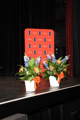 2 flower stands in front of U of I sign on graduation stage