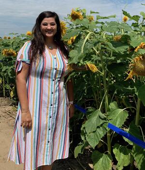 Mari Rozella wearing a striped dress in a field of sunflowers