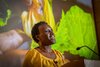 Dr Ngumbi speaking in a yellow shirt with plant presentation behind her